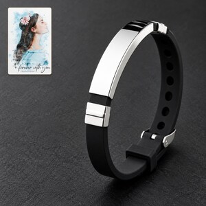 Black strap bracelet with reflective silver-tone bar and segmented end accents against charcoal slate. A personalized digital greeting card is shown alongside.