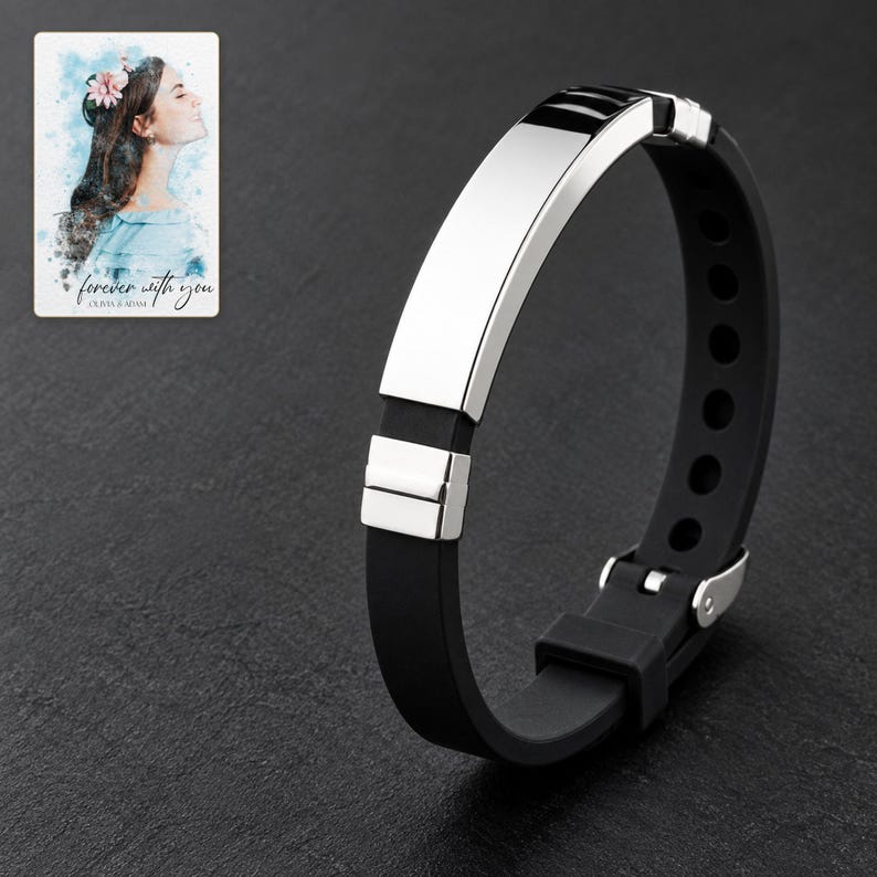 Black strap bracelet with reflective silver-tone bar and segmented end accents against charcoal slate. A personalized digital greeting card is shown alongside.