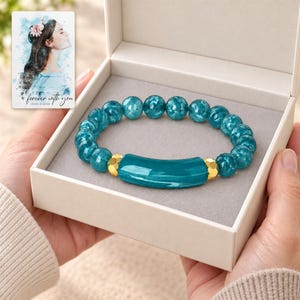 Peacock Tide Bar Bracelet shown during a believable gift-giving moment between adults with the jewelry visible. A personalized digital greeting card is shown alongside.