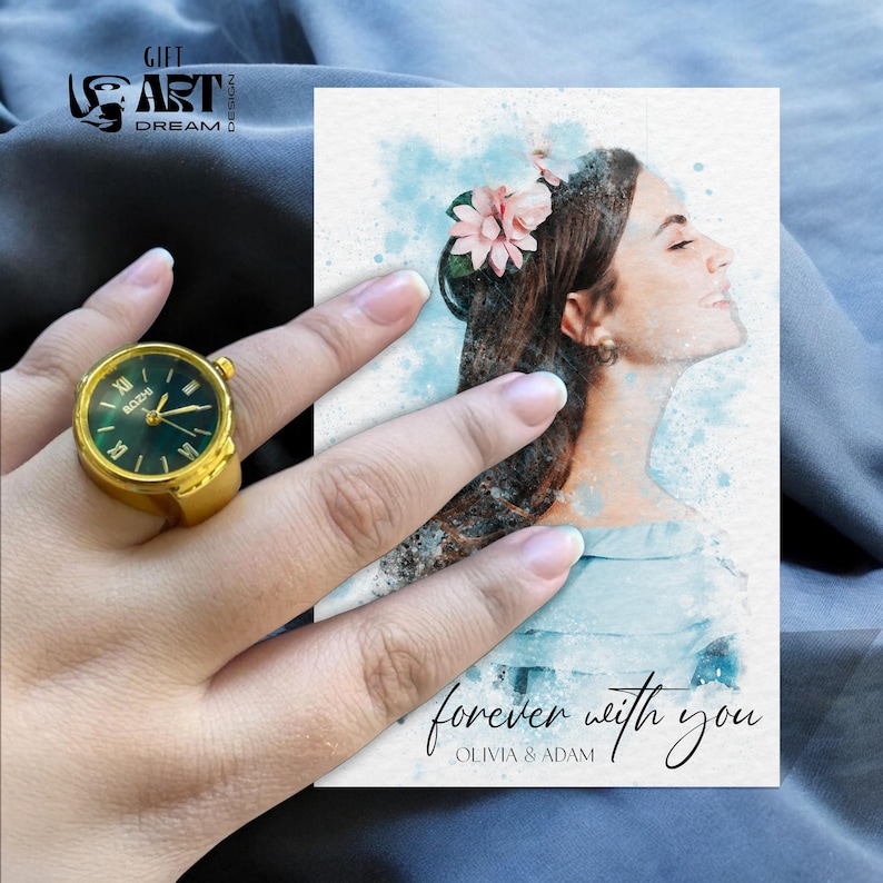 Peut inclure: Une bague-montre dor&eacute;e avec un cadran vert et des chiffres romains. La bague est sur une main &agrave; c&ocirc;t&eacute; d'une carte aquarelle avec un portrait de femme et le texte "forever with you, Olivia & Adam."