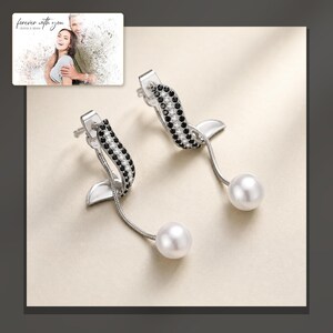 Silver-tone curved drop earrings with black accents and white round drops, dark-bordered product view. A personalized greeting-card example appears in the corner.