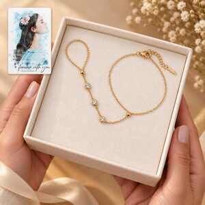 Golden Three stone style Hand Chain shown during a believable gift-giving moment between adults with the jewelry visible. A personalized digital greeting card is shown alongside.