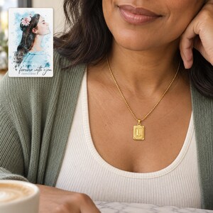 Adult woman wearing a gold tone L initial necklace with an ivory top and sage cardigan. A personalized digital greeting card is shown alongside.