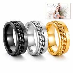 CipherSpin Roman Chain Ring shown during a believable gift-giving moment between adults with the exact jewelry visible.