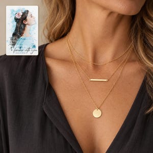 Adult woman wearing the gold-tone plain chain, slim bar and smooth disc necklaces with a charcoal blouse. A personalized digital greeting card is shown alongside.