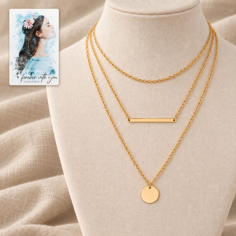 Gold-tone necklace trio on an ivory display surrounded by softly folded oatmeal linen. A personalized digital greeting card is shown alongside.