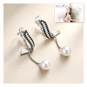 Silver-tone curved drop earrings with black accents and white round drops, catalog view. A personalized greeting-card example appears in the corner.
