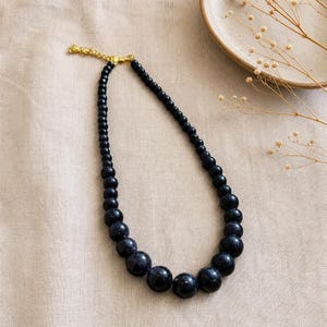 Gray and Bronze Statement Beaded Necklace presented in an open jewelry gift box on natural linen
