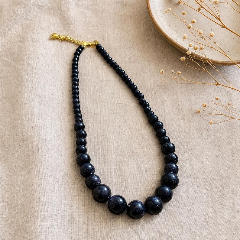 Gray and Bronze Statement Beaded Necklace presented in an open jewelry gift box on natural linen