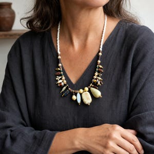 Three-piece handmade necklace set featuring clear and beige beaded necklace, silver and brown beaded necklace and red and clear beaded necklace, displayed together to show the coordinated colors and beadwork