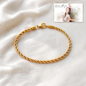 Pu&ograve; includere: Un bracciale a catena a corda color oro con chiusura a moschettone. Nell'angolo in alto a destra, una carta rettangolare mostra una fotografia in bianco e nero di una coppia con il testo "forever with you" e "OLIVIA & ADAM" stampato sopra.