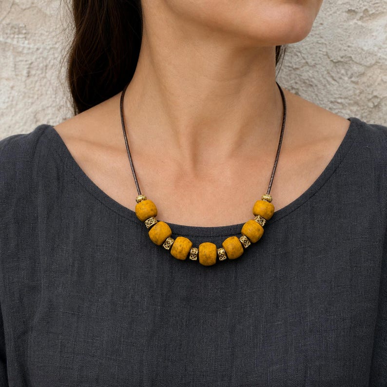 Three-piece handmade necklace set featuring mustard yellow beaded necklace, rose gold and gold beaded necklace and red beaded coin charm beaded necklace, displayed together to show the coordinated colors and beadwork