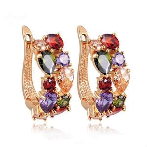 Pair of gold-tone hoop earrings with red, green, purple and clear decorative stones on a white background.