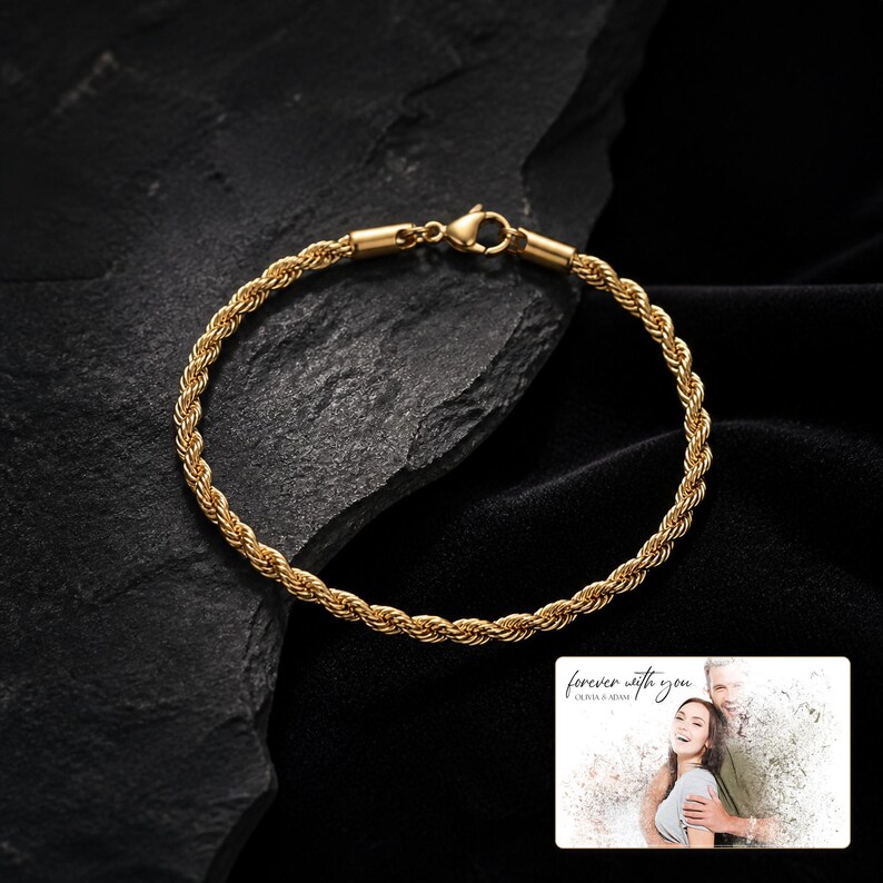 Pu&ograve; includere: Un bracciale a catena a corda color oro con chiusura a moschettone. Nell'angolo in basso a destra, una carta rettangolare mostra la fotografia di una coppia con il testo "forever with you" e "OLIVIA & ADAM" stampato in carattere corsivo e sans-serif.