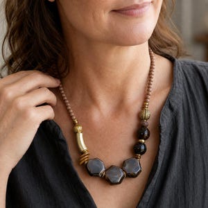 Three-piece handmade necklace set featuring brown and beige beaded necklace, purple and lavender beaded necklace and silver and brown beaded necklace, displayed together to show the coordinated colors and beadwork