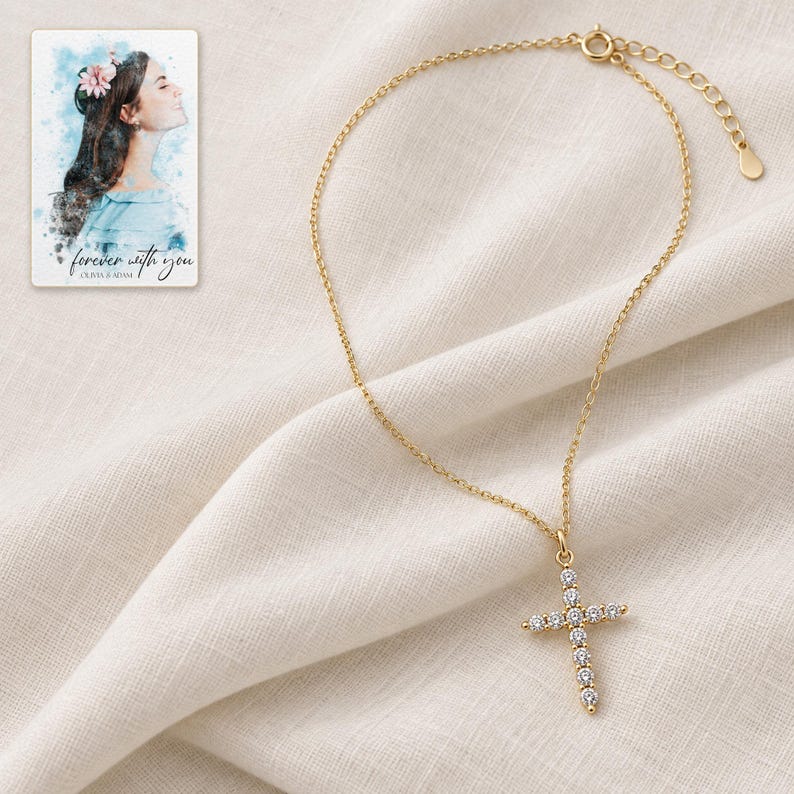 Complete gold-tone cross necklace arranged on ivory linen with the clasp and extension links visible. A personalized digital greeting card is shown alongside.