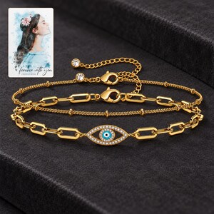 Gold Tone Evil Eye Bracelet Duo styled against a dark luxury surface with the visible finish clearly visible. A personalized digital greeting card is shown alongside.