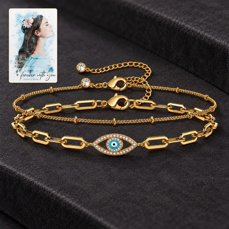 Gold Tone Evil Eye Bracelet Duo styled against a dark luxury surface with the visible finish clearly visible. A personalized digital greeting card is shown alongside.
