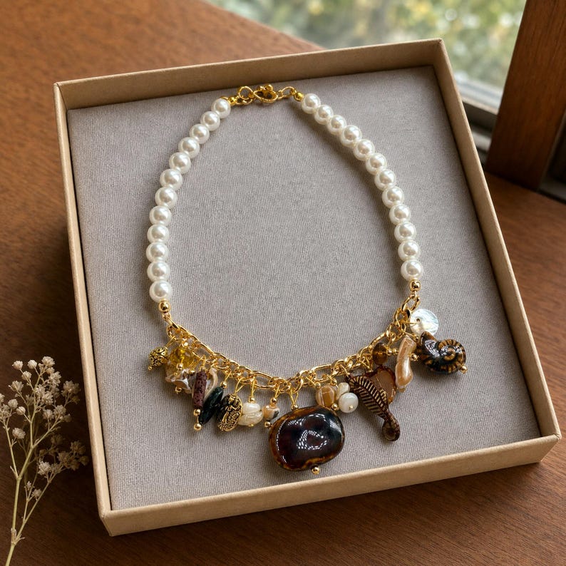 Ivory pearl style gold tone brown cream charm statement necklace worn with an ivory linen top in warm natural window light