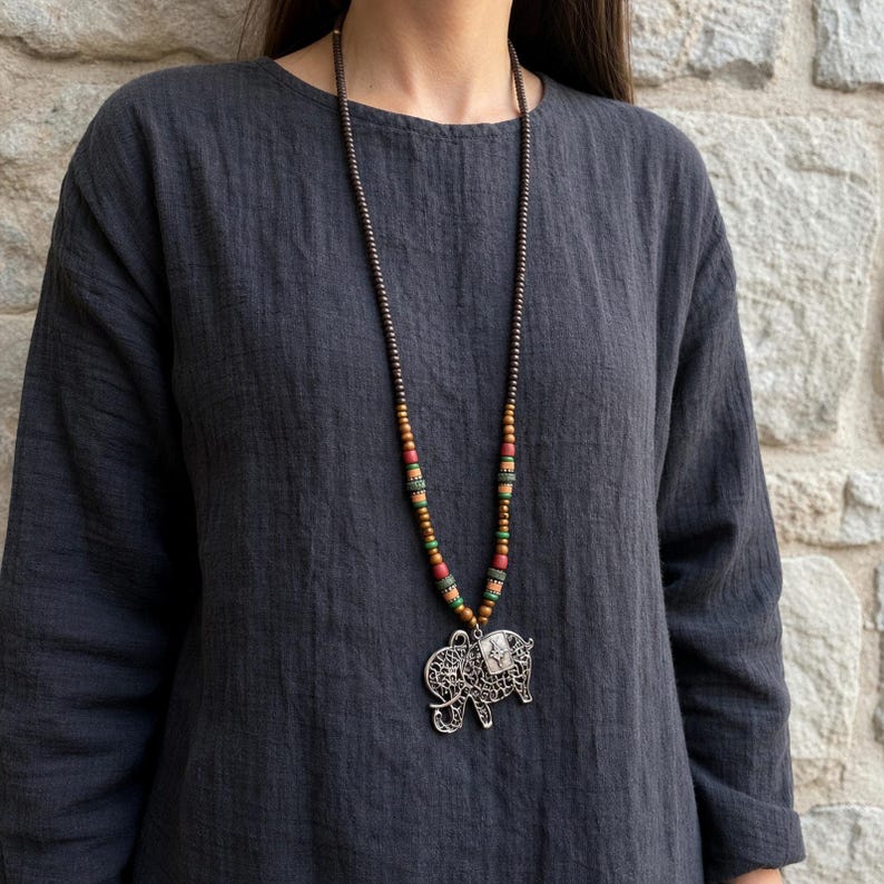 Three-piece handmade necklace set featuring elephant pendant beaded necklace, antique gold leaf charm beaded necklace and turquoise beaded fish evil eye beaded necklace, displayed together to show the coordinated colors and beadwork