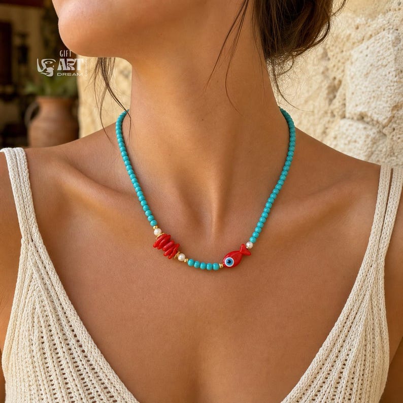 Turquoise Beaded Fish Evil Eye Necklace presented in an open jewelry gift box on natural linen