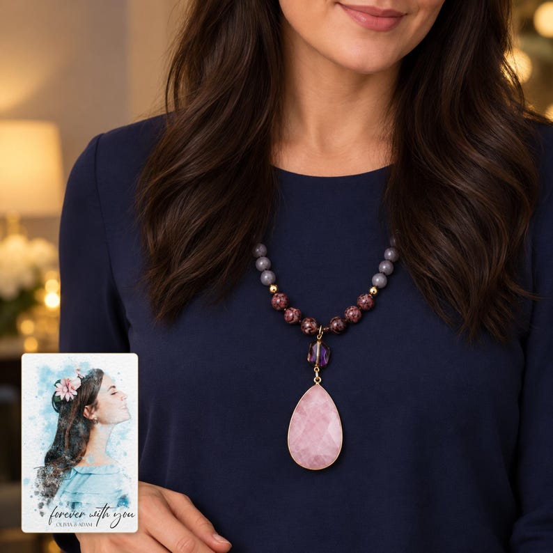 Adult wearing the pink pendant necklace over navy clothing; the lower bead groups and teardrop show beneath the hair. A personalized digital greeting card is shown alongside.
