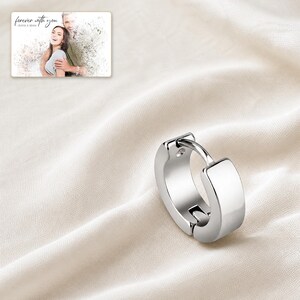 EdgeLine Stainless Huggie Hoops shown during a believable gift-giving moment between adults with the exact jewelry visible.