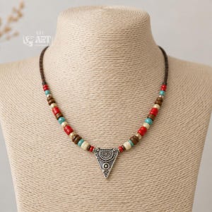 On-model lifestyle photo of multicolor beaded silver tone triangle pendant necklace worn with neutral clothing