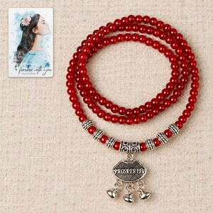 Crimson Agate style Charm Wrap Bracelet arranged on soft ivory linen in a refined neutral flat lay. A personalized digital greeting card is shown alongside.