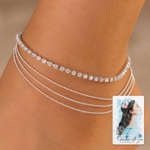 Silver Starlight Layered Anklet shown during a warm gift-receiving moment between adults with the exact jewelry visible.