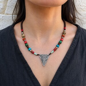 Three-piece handmade necklace set featuring multicolor triangle pendant beaded necklace, antique gold leaf charm beaded necklace and turquoise beaded fish evil eye beaded necklace, displayed together to show the coordinated colors and beadwork