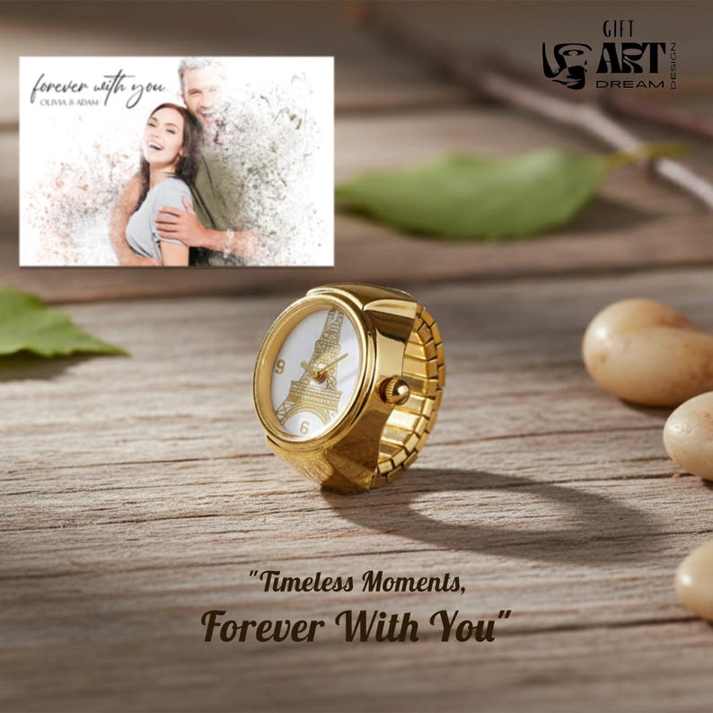 May include: A gold ring watch with a white face displaying the Eiffel Tower and the numbers 6 and 9. The ring sits on a wooden surface with the text "Timeless Moments, Forever With You". A photo of a couple is in the background.