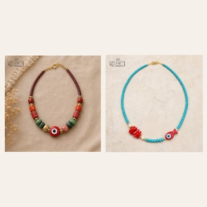 Puede incluir: Dos collares. El de la izquierda tiene cuentas marrones, rojas y verdes con un amuleto central de ojo rojo. El de la derecha consta de peque&ntilde;as cuentas turquesas, piezas rojas similares al coral y un dije de ojo en forma de pez rojo.