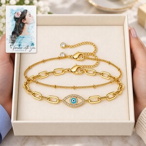 Gold Tone Evil Eye Bracelet Duo shown during a believable gift-giving moment between adults with the jewelry visible. A personalized digital greeting card is shown alongside.