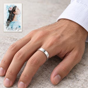 An adult wearing the smooth silver-tone open band ring with neutral daywear. A personalized digital greeting card is shown alongside.