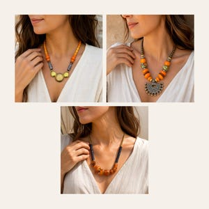 May include: Three distinct necklaces featuring orange and black beads. The first has yellow-gold circular accents, the second displays a large silver-toned fan-shaped pendant, and the third showcases a mix of dark beads with amber-toned center pieces.