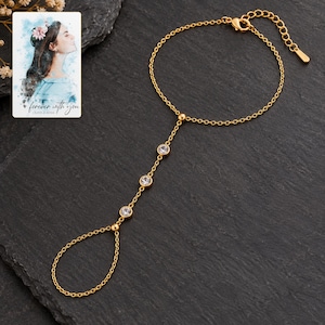 Golden Three stone style Hand Chain styled against a dark luxury surface with the exact product finish clearly visible. A personalized digital greeting card is shown alongside.