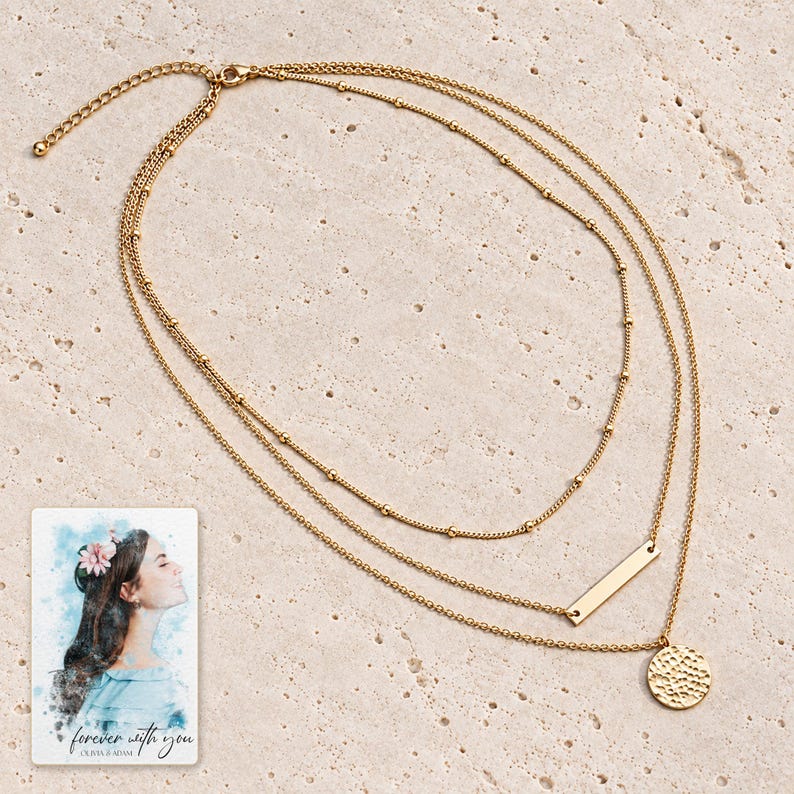 Close construction view of the complete satellite, narrow bar and hammered coin necklace on a pale surface. A personalized digital greeting card is shown alongside.