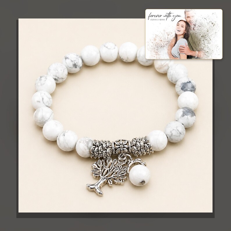 White and gray bead bracelet with silver-tone tree and hanging bead details, dark-bordered product view. A personalized greeting-card example appears in the corner.