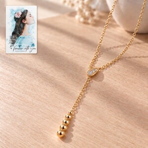 Moissanite Y Necklace, sunlit home view. A personalized digital greeting card is shown alongside.