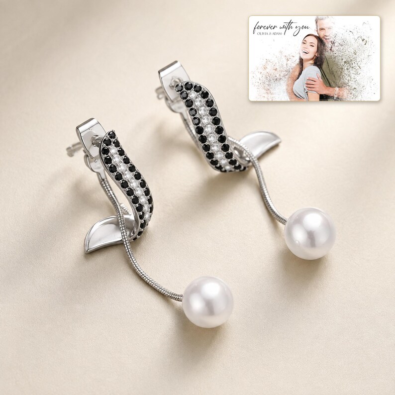Silver-tone curved drop earrings with black accents and white round drops, display view. A personalized greeting-card example appears in the corner.