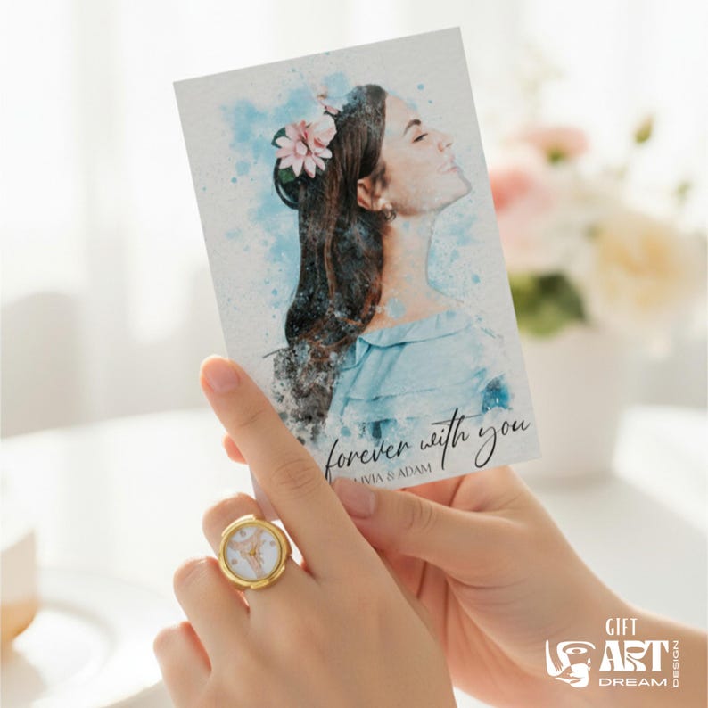 May include: A gold ring with a white face and a watercolour print card with a woman's portrait. The card has the text "forever with you" and is held in a person's hands. The ring is on the person's finger.