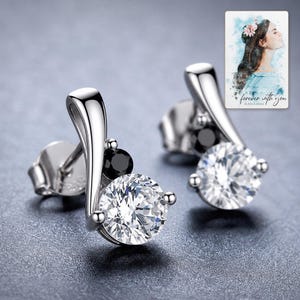 Adult woman receiving the black and clear zircon stud earrings in an open jewelry box from another adult woman.