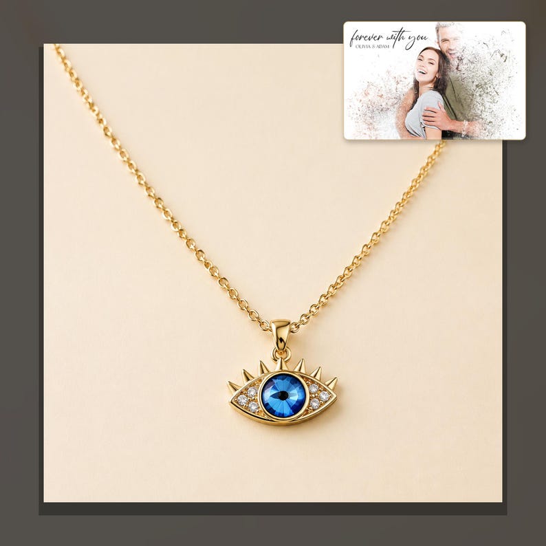 Gold-tone necklace with a blue eye-shaped pendant, dark-bordered product view. A personalized greeting-card example appears in the corner.