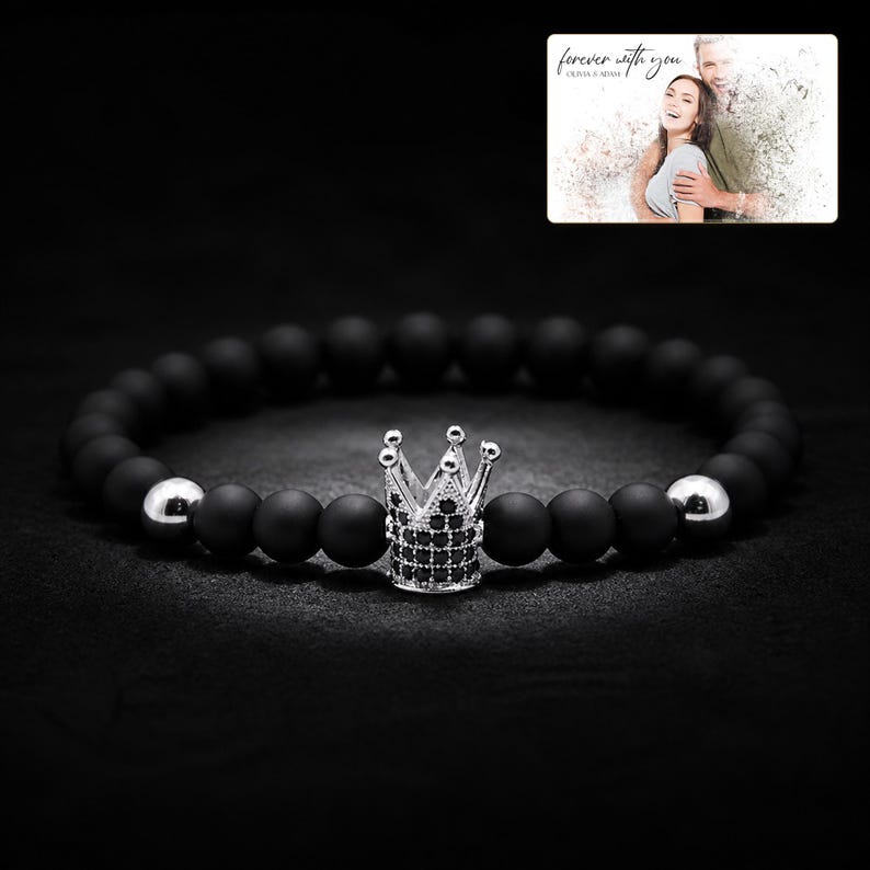 Puede incluir: Una pulsera de cuentas con esferas negras mate, dos esferas plateadas pulidas y un dije central de corona plateada incrustado con peque&ntilde;as piedras negras. Una foto muestra a una pareja con el texto forever with you.
