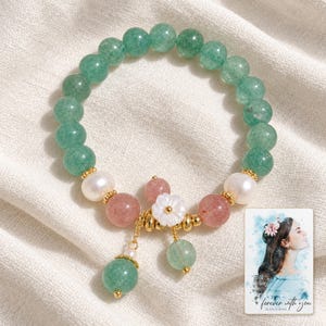 Forest Strawberry clear accents Bracelet arranged on soft ivory linen in a refined neutral flat lay. A personalized digital greeting card is shown alongside.