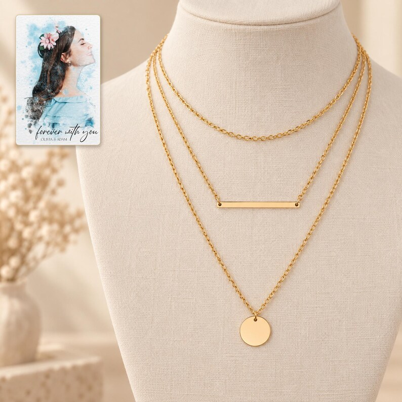 Complete gold-tone necklace trio on an ivory fabric display, with three descending oval-link chains and a smooth bar and disc. A personalized digital greeting card is shown alongside.
