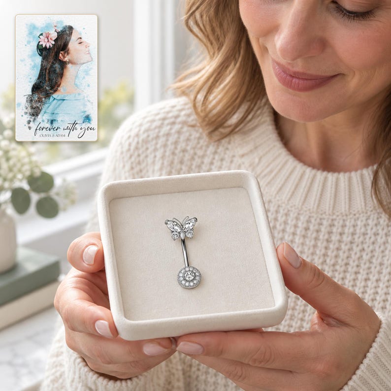 A fully clothed adult holds a small open tray displaying the exact butterfly navel bar in daylight. A personalized digital greeting card is shown alongside.