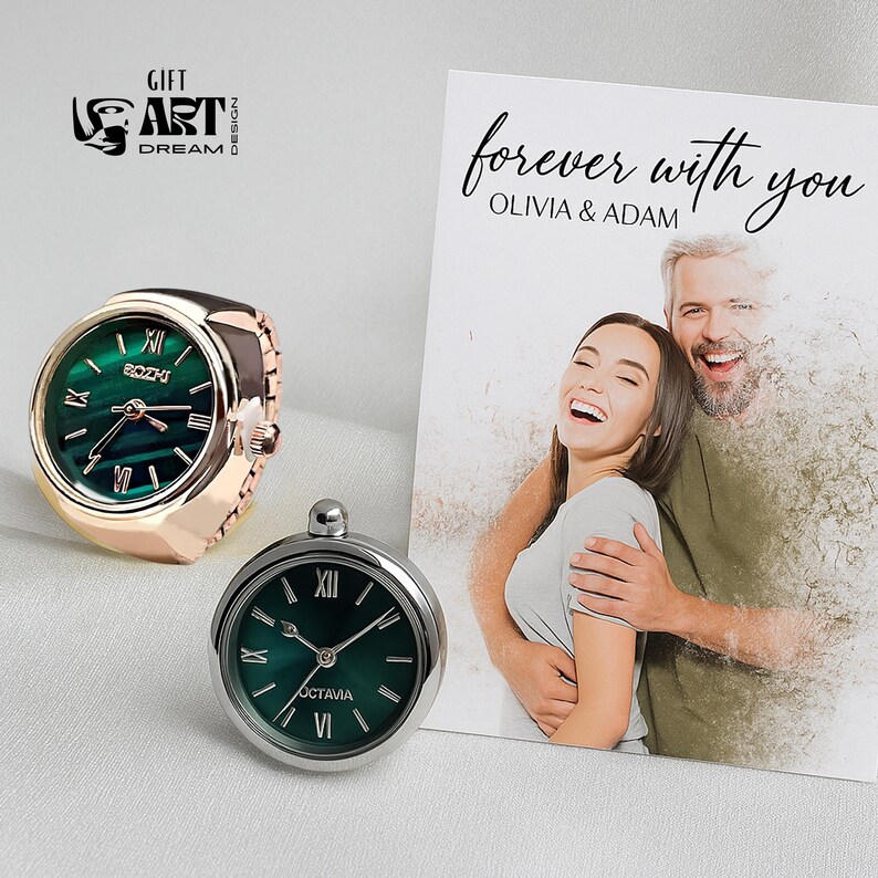 Peut inclure: Deux bagues-montres et une carte avec le texte "forever with you". Une bague-montre est en or rose avec un cadran vert, l'autre est en argent avec un cadran vert. La carte pr&eacute;sente une photo d'un couple.