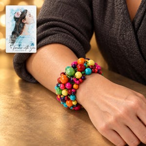 Rainbow Bead Bracelet worn by an adult in a polished evening lifestyle scene. A personalized digital greeting card is shown alongside.